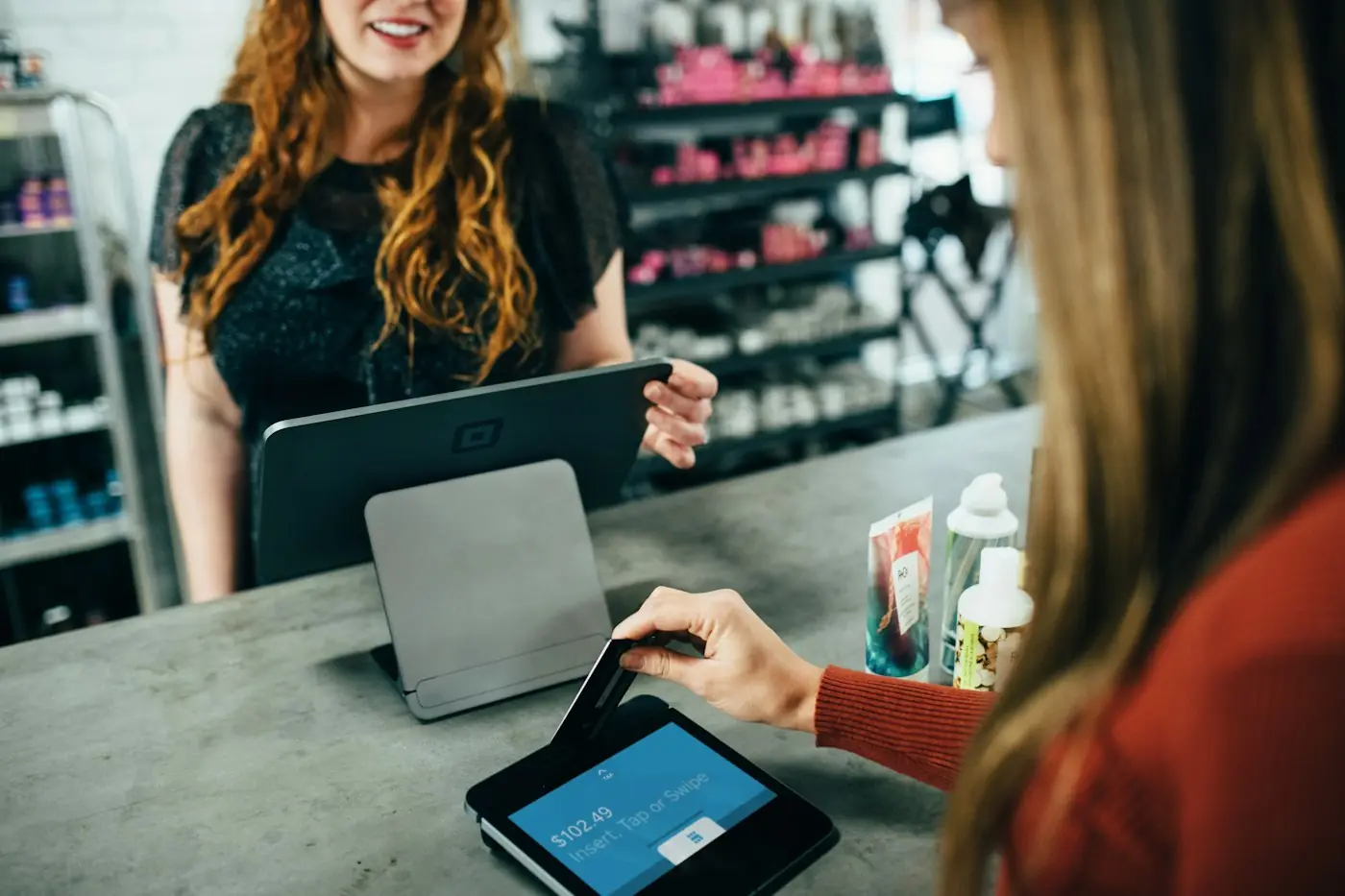 Dona de loja atendendo uma cliente no balcão com um tablet