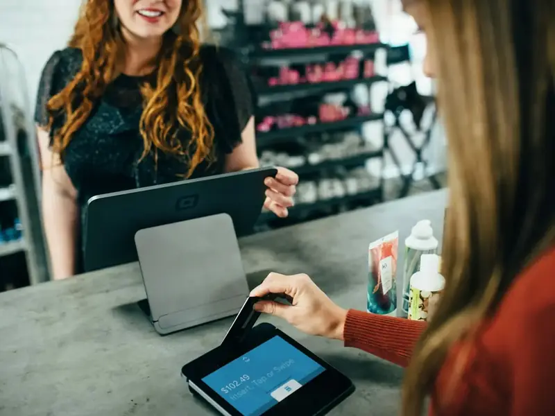 Dona de loja atendendo uma cliente no balcão com um tablet