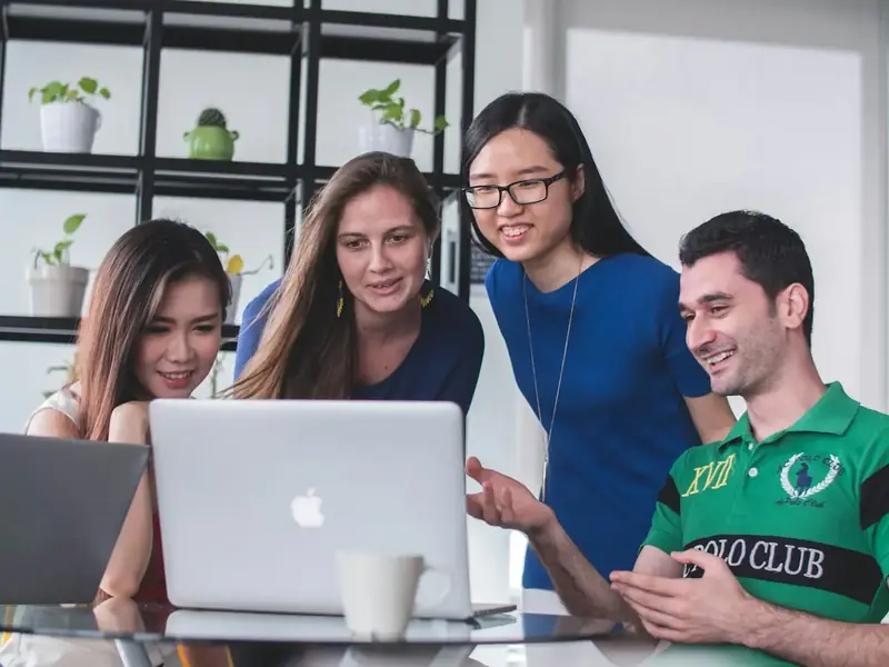 Equipe comercial reunida em volta de um notebook