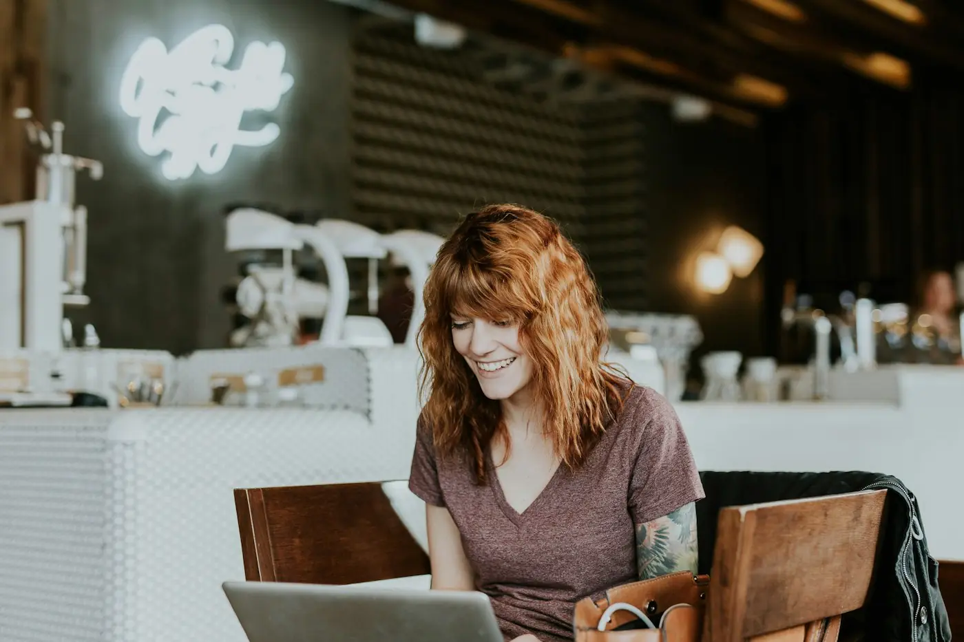Mulher sorrindo enquanto usa o notebook em um café